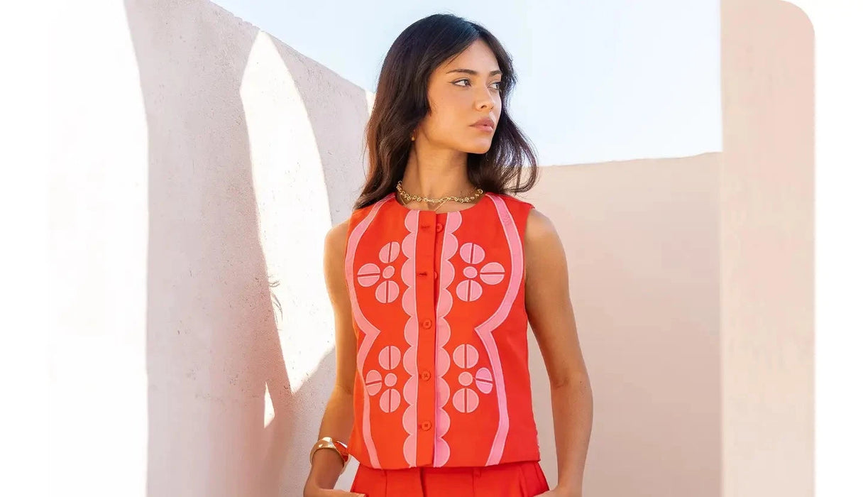 Woman wearing a red sleeveless top and shorts with floral patterns against a white background